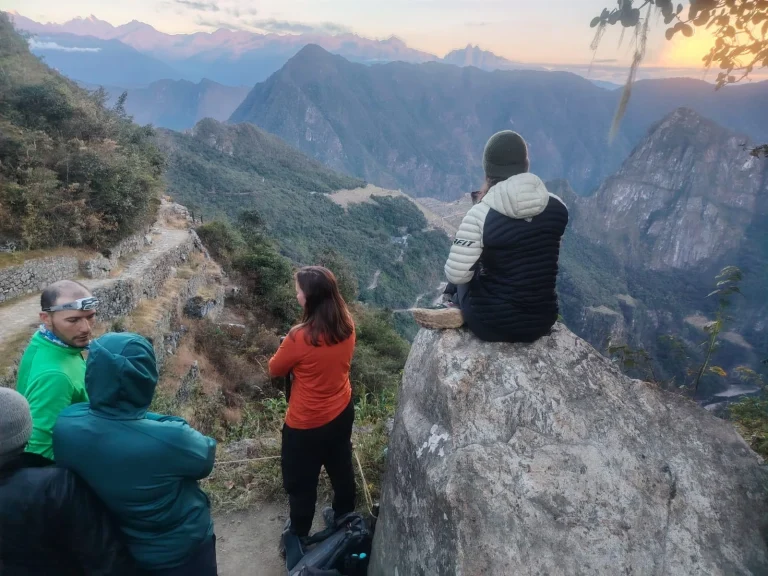 Hikers at sunrise near the Sun Gate (Inti Punku) looking down at Machu Picchu