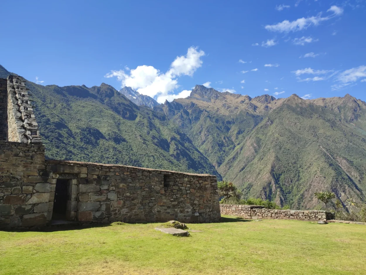 Inca building on a grassy plaza at Choquequirao with mountains behind