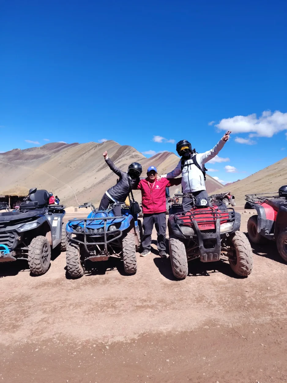 Travelers celebrating next to their ATVs below Rainbow Mountain with their Salas Travel guide