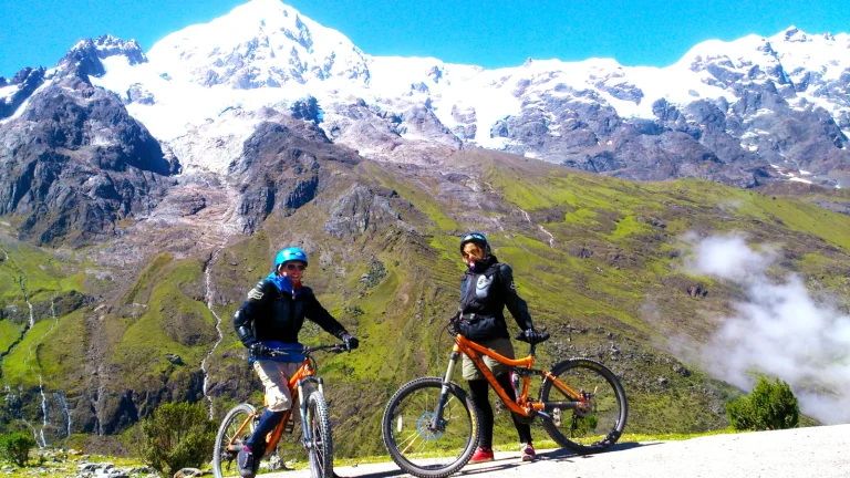 Two cyclists with mountain bikes below snow-capped peaks at the start of the Inca Jungle trek