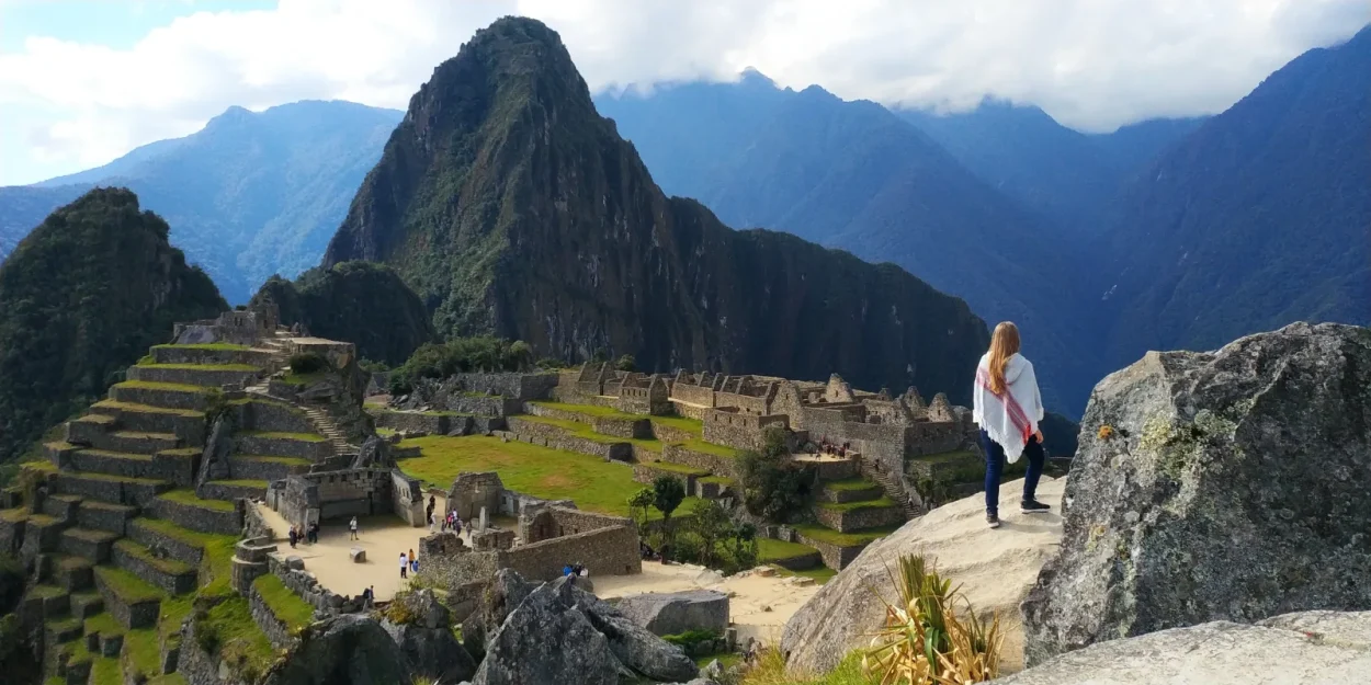 Traveler looking at Machu Picchu and Huayna Picchu from the upper terraces