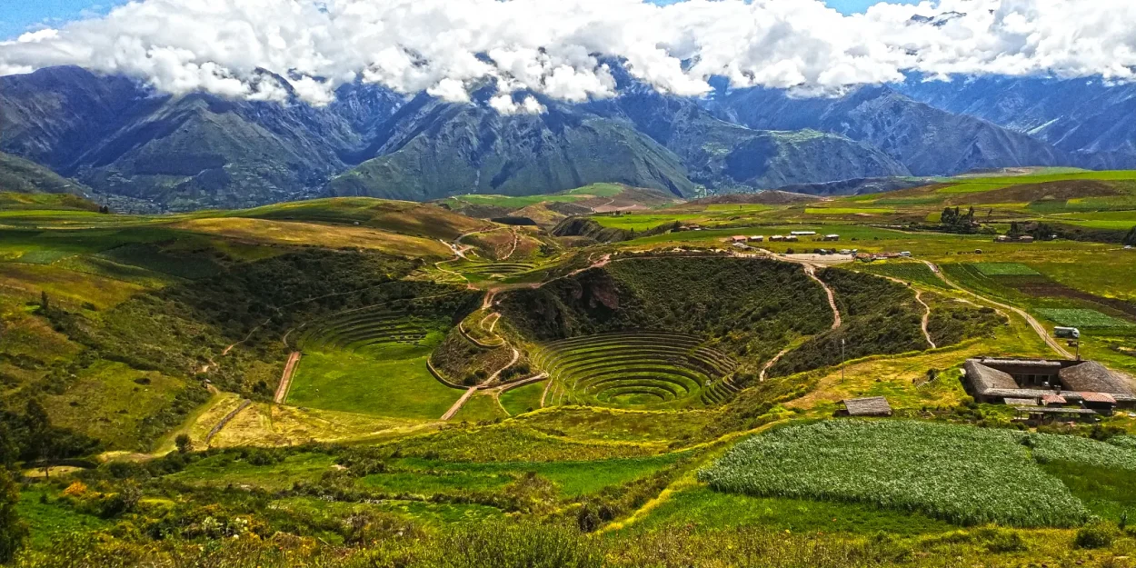 Circular Inca terraces of Moray among green fields, with mountains behind