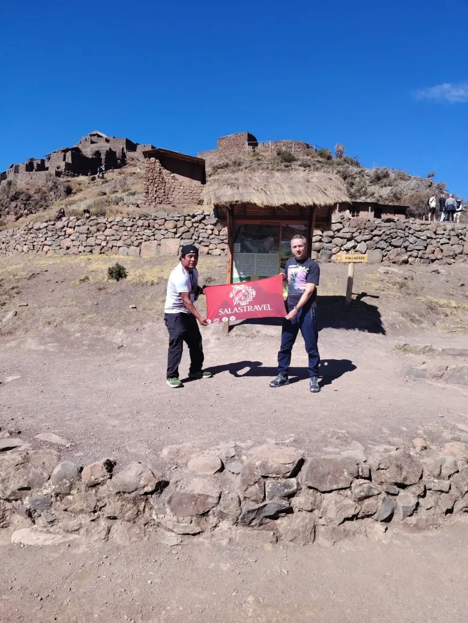 Salas Travel guide and a traveler with the company flag in the K'allaq'asa sector of the Pisac archaeological site